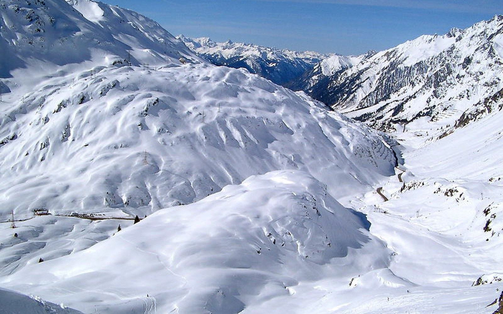 Snow-covered mountain slopes surround a winding road cutting through the Arlberg pass