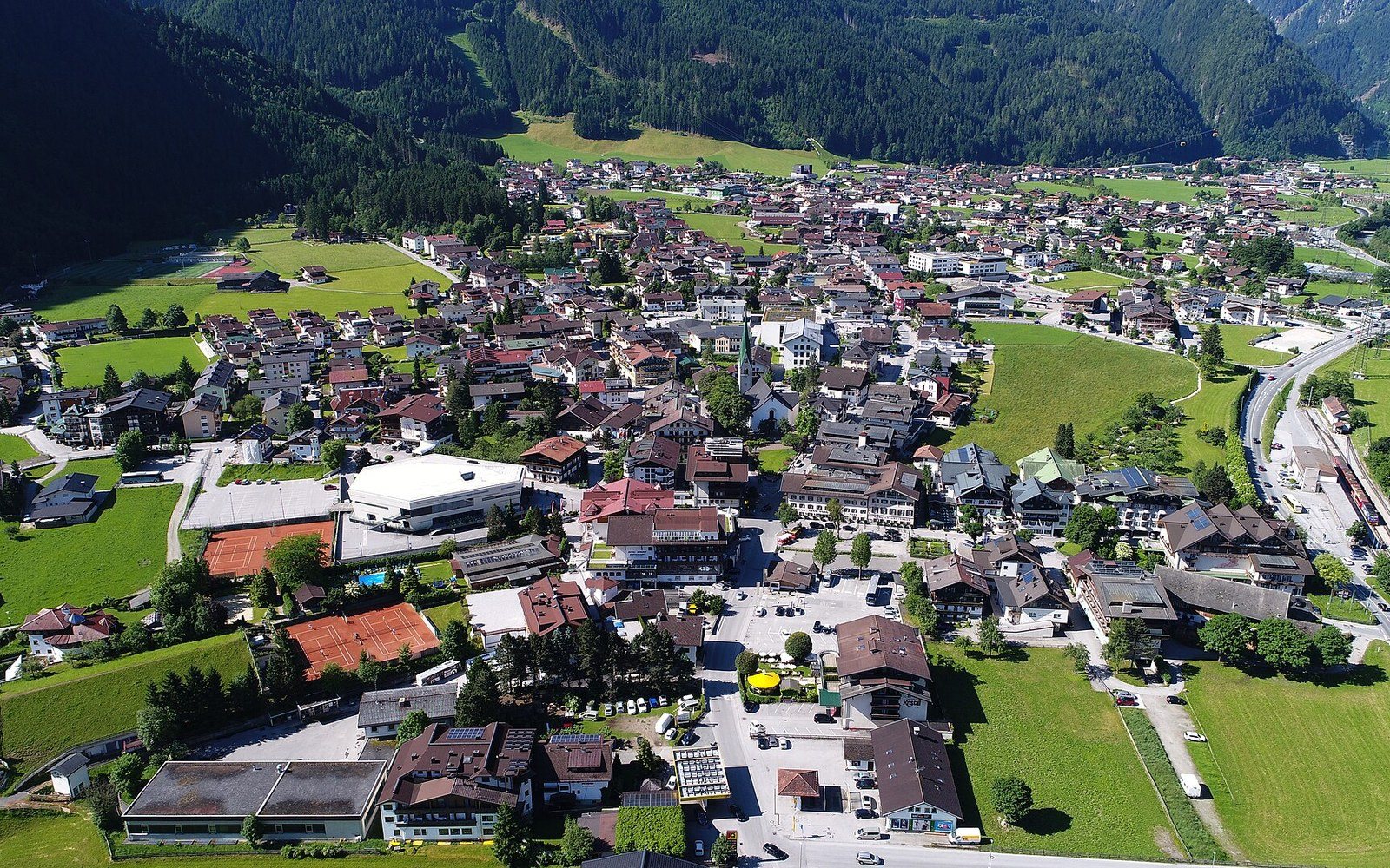 Aerial view of Mayrhofen village nestled in a green alpine valley surrounded by forested mountains